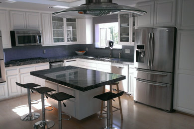 Inspiration for a contemporary u-shaped light wood floor and beige floor open concept kitchen remodel in Los Angeles with an undermount sink, raised-panel cabinets, white cabinets, gray backsplash, stainless steel appliances and an island