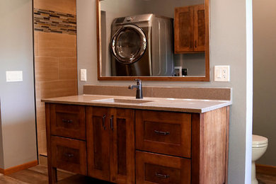 Inspiration for a mid-sized timeless master beige tile and ceramic tile vinyl floor and gray floor bathroom remodel in Other with flat-panel cabinets, medium tone wood cabinets, a two-piece toilet, gray walls, an integrated sink, onyx countertops and beige countertops