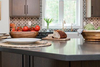 Example of a tuscan medium tone wood floor eat-in kitchen design in Baltimore with light wood cabinets, multicolored backsplash, cement tile backsplash, stainless steel appliances, an island and gray countertops