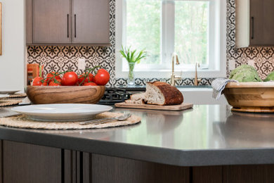 Foto de cocina comedor mediterránea con puertas de armario de madera clara, salpicadero multicolor, salpicadero de azulejos de cemento, electrodomésticos de acero inoxidable, suelo de madera en tonos medios, una isla y encimeras grises