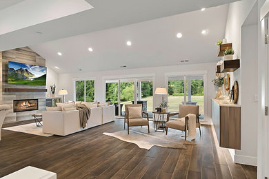 Example of an open concept medium tone wood floor and brown floor living room design in Seattle with white walls