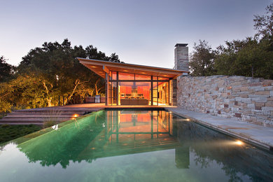 Pool - large contemporary backyard stone and rectangular infinity pool idea in Orange County