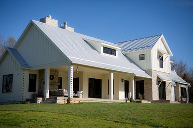 This is an example of a large country two-storey white house exterior in Other with concrete fiberboard siding, a gable roof and a metal roof.