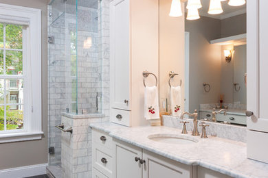 Corner shower - large traditional master gray tile and marble tile porcelain tile and gray floor corner shower idea in Detroit with recessed-panel cabinets, white cabinets, brown walls, an undermount sink, marble countertops and a hinged shower door