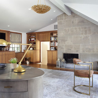 ニューヨークの大きいモダンスタイルのおしゃれな書斎 (グレーの壁、無垢フローリング、標準型暖炉、石材の暖炉まわり、自立型机、茶色い床) の写真