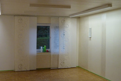 Imagen de sótano en el subsuelo contemporáneo de tamaño medio con paredes blancas y suelo de madera clara
