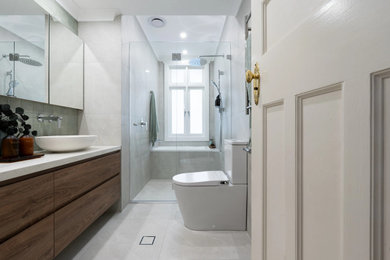 Design ideas for a large modern kids wet room bathroom in Sydney with flat-panel cabinets, medium wood cabinets, a drop-in tub, a bidet, gray tile, grey walls, a vessel sink, grey floor, a hinged shower door, beige benchtops, a double vanity and a floating vanity.