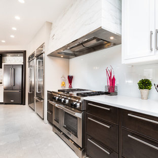 Huge contemporary kitchen pantry photos - Inspiration for a huge contemporary l-shaped travertine floor kitchen pantry remodel in Albuquerque with white backsplash, glass sheet backsplash, stainless steel appliances, black cabinets, an island, flat-panel cabinets and quartz countertops