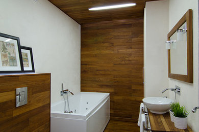На фото: главная ванная комната среднего размера в современном стиле с плоскими фасадами, фасадами цвета дерева среднего тона, гидромассажной ванной, душем над ванной, паркетным полом среднего тона, настольной раковиной и столешницей из дерева с