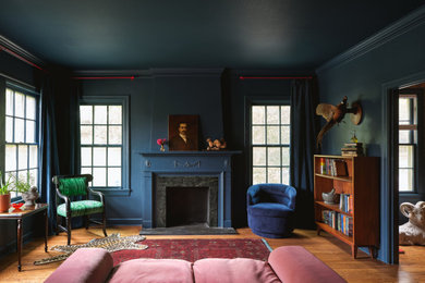Foto de salón actual con paredes azules, suelo de madera en tonos medios, todas las chimeneas, marco de chimenea de piedra, bandeja, suelo marrón y boiserie