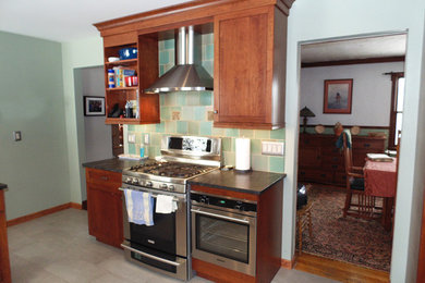 Example of a mid-sized classic u-shaped ceramic tile and beige floor eat-in kitchen design in New York with a farmhouse sink, recessed-panel cabinets, medium tone wood cabinets, green backsplash, porcelain backsplash, stainless steel appliances and no island