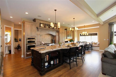 Example of a huge trendy medium tone wood floor kitchen design in St Louis with a double-bowl sink, light wood cabinets, granite countertops, multicolored backsplash, paneled appliances and an island