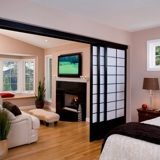 Esempio di una grande camera matrimoniale etnica con pareti beige, parquet chiaro, camino classico, cornice del camino in pietra e pavimento marrone