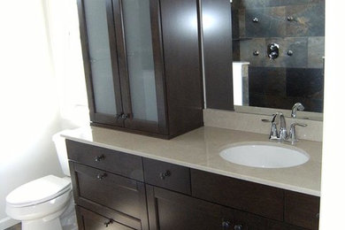 Example of a large transitional master multicolored tile and stone tile slate floor alcove shower design in New York with recessed-panel cabinets, dark wood cabinets, quartz countertops, a two-piece toilet, white walls and an undermount sink