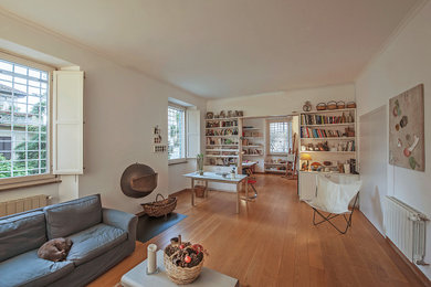 Imagen de biblioteca en casa abierta contemporánea con suelo de madera en tonos medios, todas las chimeneas y marco de chimenea de metal