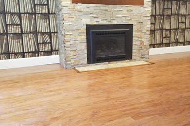 Photo of a traditional living room with multi-coloured walls, light hardwood floors, a standard fireplace, a stone fireplace surround and brown floor.