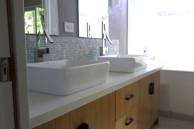 Inspiration for a small contemporary master mosaic tile ceramic tile bathroom remodel in San Francisco with flat-panel cabinets, light wood cabinets, a one-piece toilet, gray walls, a vessel sink and solid surface countertops