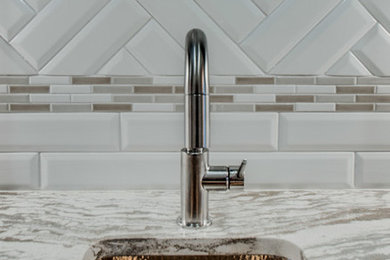 Inspiration for a mid-sized transitional galley dark wood floor and brown floor enclosed kitchen remodel in Nashville with an undermount sink, recessed-panel cabinets, blue cabinets, granite countertops, white backsplash, porcelain backsplash, stainless steel appliances and no island