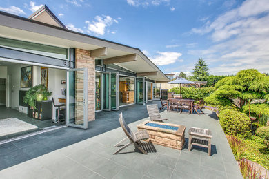 Inspiration for a mid-sized 1960s backyard stone patio remodel in Seattle with a roof extension