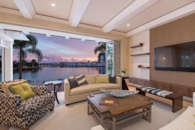 Photo of a mid-sized transitional enclosed living room in Miami with beige walls, light hardwood floors, a wall-mounted tv and beige floor.