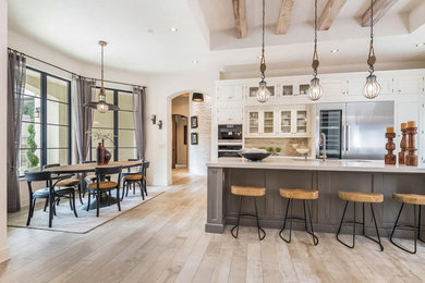 This is an example of an expansive traditional u-shaped eat-in kitchen in Seattle with an undermount sink, beaded inset cabinets, white cabinets, white splashback, stainless steel appliances, painted wood floors, with island, white floor and white benchtop.