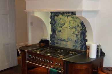 Enclosed kitchen - mid-sized single-wall medium tone wood floor enclosed kitchen idea in Salt Lake City with raised-panel cabinets, dark wood cabinets, solid surface countertops, multicolored backsplash, mosaic tile backsplash, stainless steel appliances and no island