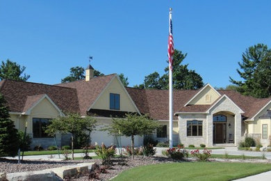 Inspiration for a large timeless yellow two-story mixed siding exterior home remodel in Milwaukee with a shingle roof