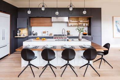 Modern l-shaped kitchen in Seattle with flat-panel cabinets, grey cabinets, granite benchtops, white splashback, stone slab splashback, panelled appliances, light hardwood floors and white benchtop.