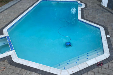 Imagen de piscina tradicional de tamaño medio a medida en patio trasero con adoquines de hormigón