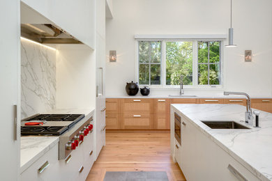 Example of a trendy medium tone wood floor kitchen design in San Francisco with an undermount sink, flat-panel cabinets, white cabinets, gray backsplash, stone slab backsplash, stainless steel appliances and an island