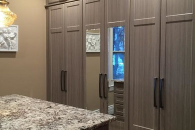 Walk-in closet - mid-sized contemporary gender-neutral dark wood floor walk-in closet idea in New York with shaker cabinets and gray cabinets