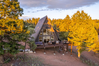 Small rustic gray two-story exterior home idea in Other with a brown roof