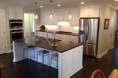 Inspiration for a contemporary l-shaped dark wood floor eat-in kitchen remodel in Charlotte with an undermount sink, shaker cabinets, white cabinets, soapstone countertops, white backsplash, porcelain backsplash, stainless steel appliances and an island