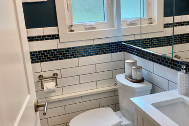 Inspiration for a small transitional blue tile and mosaic tile vinyl floor, brown floor and wainscoting powder room remodel in Other with shaker cabinets, white cabinets, a two-piece toilet, blue walls, an undermount sink, quartz countertops, white countertops and a built-in vanity