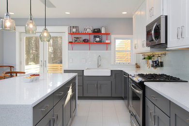 Kitchen - large transitional l-shaped porcelain tile kitchen idea in Philadelphia with a farmhouse sink, shaker cabinets, white backsplash, glass tile backsplash, an island, white cabinets, quartzite countertops and stainless steel appliances