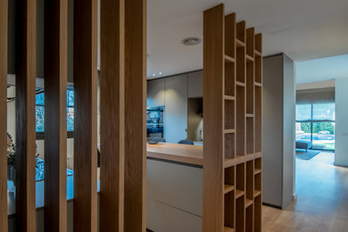 Imagen de cocina lineal actual de tamaño medio abierta con armarios con paneles lisos, puertas de armario grises, encimera de cuarzo compacto, península, salpicadero verde, encimeras grises, fregadero bajoencimera y suelo de madera en tonos medios