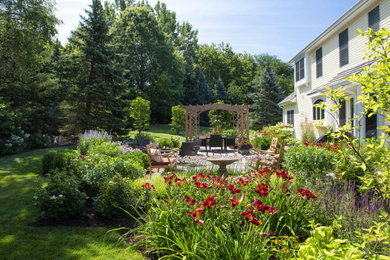Example of a large classic backyard stone patio fountain design in Chicago with a pergola