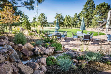 Photo of a large mediterranean drought-tolerant and full sun backyard concrete paver landscaping in Denver.