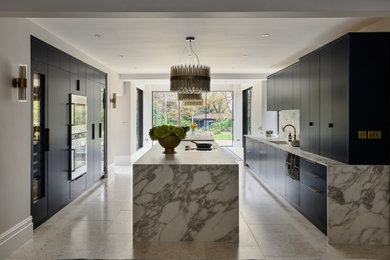 Photo of a contemporary galley kitchen in Surrey with a submerged sink, flat-panel cabinets, black cabinets, white splashback, stone slab splashback, an island, grey floors and white worktops.