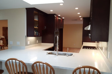 Enclosed kitchen - small contemporary u-shaped light wood floor and brown floor enclosed kitchen idea in San Francisco with an undermount sink, shaker cabinets, dark wood cabinets, quartz countertops, gray backsplash, glass tile backsplash, stainless steel appliances and a peninsula