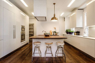 Kitchen - mid-sized traditional l-shaped dark wood floor kitchen idea in Philadelphia with flat-panel cabinets, white cabinets, white appliances and an island