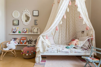 Photo of a small transitional kids' bedroom for kids 4-10 years old and girls in Seville with beige walls, medium hardwood floors and brown floor.