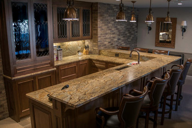 Mid-sized minimalist u-shaped home bar photo in Cleveland with shaker cabinets, medium tone wood cabinets, beige backsplash and stone slab backsplash