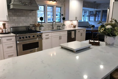 Photo of a large midcentury eat-in kitchen in Other with an undermount sink, shaker cabinets, white cabinets, quartzite benchtops, white splashback, stone tile splashback, stainless steel appliances, medium hardwood floors, with island and white benchtop.
