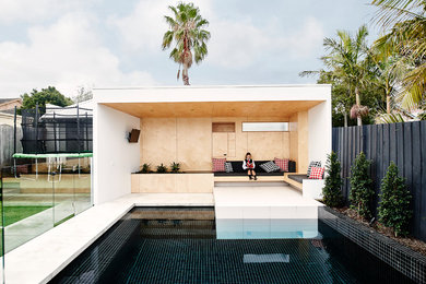 Contemporary backyard rectangular lap pool in Melbourne with a pool house and tile.