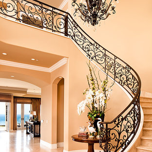 Design ideas for a large mediterranean curved metal railing staircase in Orange County with travertine treads and travertine risers.