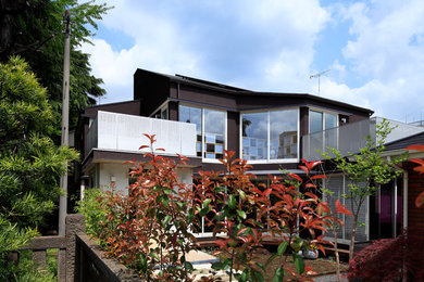 Photo of a mid-sized traditional two-storey brown house exterior in Tokyo with a shed roof and a metal roof.