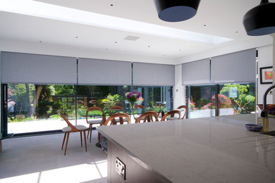 Esempio di una grande sala da pranzo aperta verso la cucina design con pareti bianche, pavimento con piastrelle in ceramica e pavimento grigio
