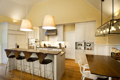 Inspiration for a large timeless l-shaped medium tone wood floor and brown floor eat-in kitchen remodel in Philadelphia with shaker cabinets, white cabinets, white backsplash, subway tile backsplash, stainless steel appliances and an island