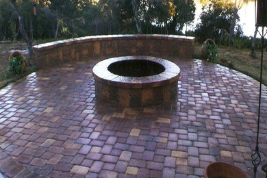 This is an example of a medium sized back patio in Orlando with a fire feature and brick paving.